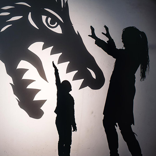 Photo de deux personnes dans l'ombre avec une représentation d'un dragon