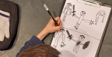 Photo d'un enfant réalisant un dessin sur une feuille blanche