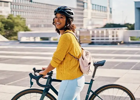 Une femme souriante arrive au travail avec son vélo.
