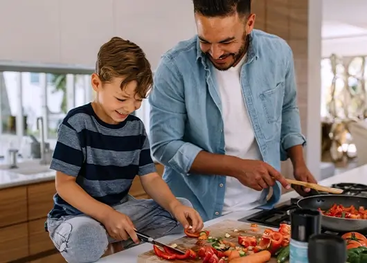 Un père et son fils cuisinent ensemble des légumes.